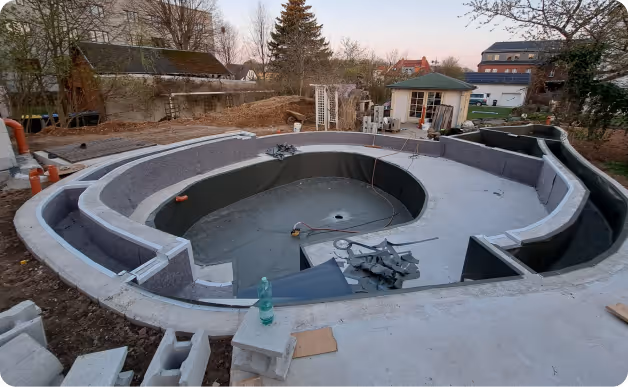 Im Bau befindliches, in den Boden eingelassenes Becken in einem Garten mit Konstruktion aus Beton und Ziegeln.